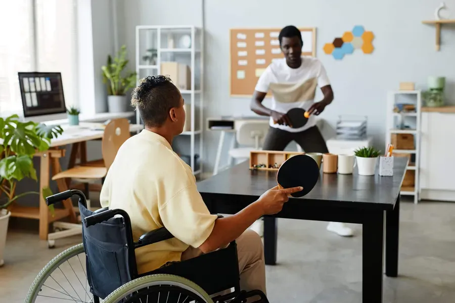 A man using a wheelchair playing table tennis in a community space