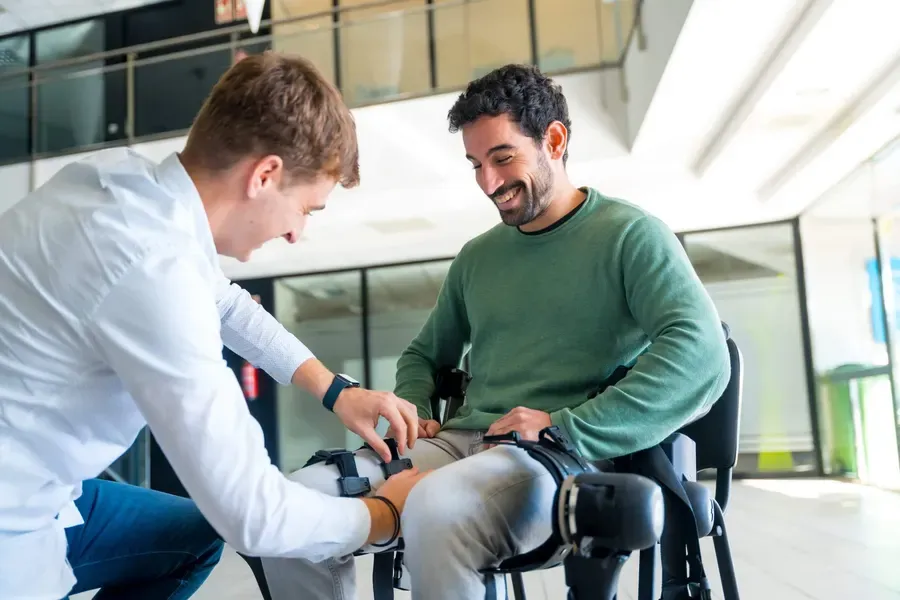 A physiotherapist fitting a mechanical exoskeleton to a client